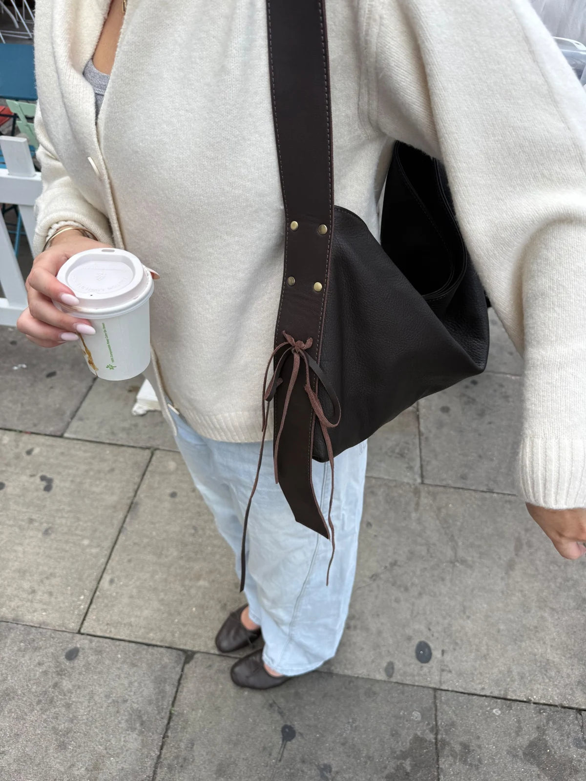 A close-up of a dark KÖVI shoulder bag styled with a light cardigan